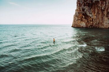 Un homme debout dans la mer avec une falaise