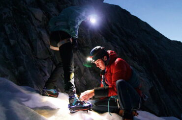 Deux alpinistes qui s'aident dans la nuit