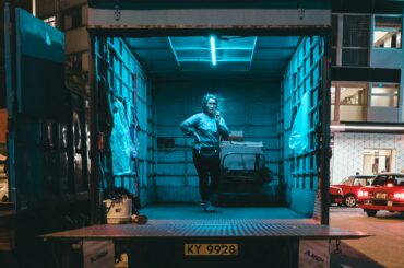 Femme debout dans un camion de déménagement presque vide, éclairé au néon, la nuit