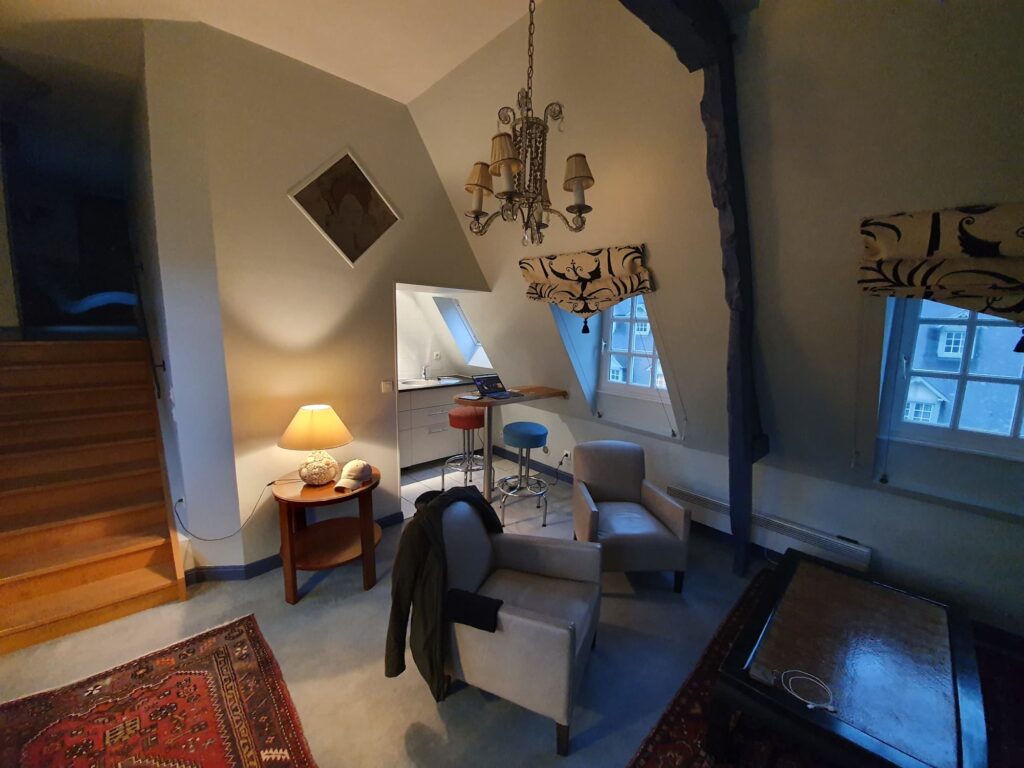 Salon de la Suite d’Exception de l’hôtel Douce France à Veules-les-Roses, avec son escalier vers l’étage sous les toits
